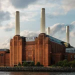 Exterior view of Battersea Power Station with its four iconic chimneys against a cloudy sky