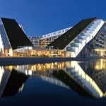 Can architecture really solve social problems? This critical essay examines Bjarke Ingels’ optimistic design philosophy, public architecture, sustainability, accessibility, and the limits of architectural agency.