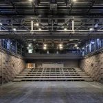 Empty black-box style theatre space with flexible seating and technical grid