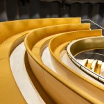 weeping golden staircase and curved wall within the new Children’s Opera volume