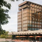 Closer exterior of Royale Belge showing the Modernist tower among mature trees