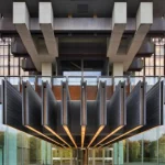 Dramatic underside view of the building’s elevated structure and fountain or water feature