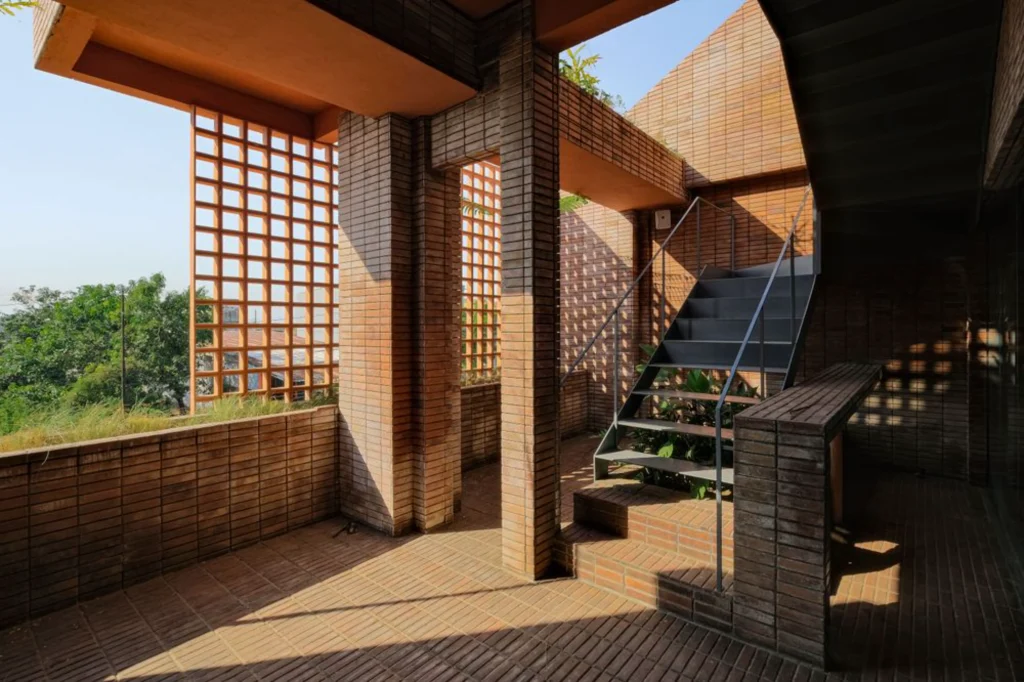 Exterior corner of Common Days with terracotta brick screens and open upper terrace overlooking the landscape