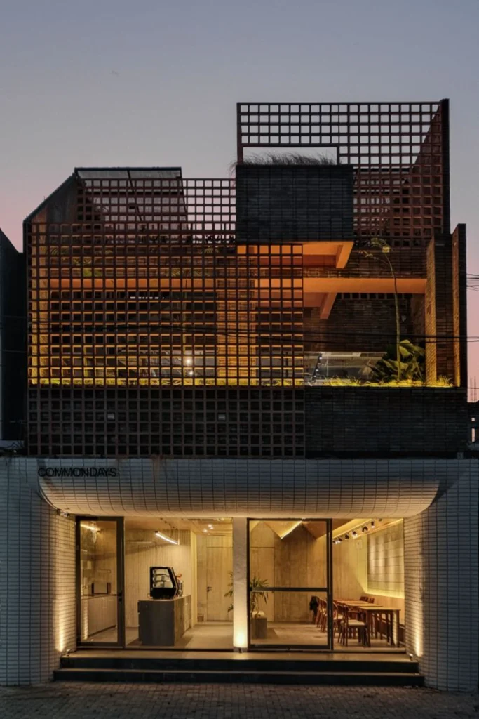 Front elevation of the three-story building showing ground-floor openness and upper-level terracotta screens