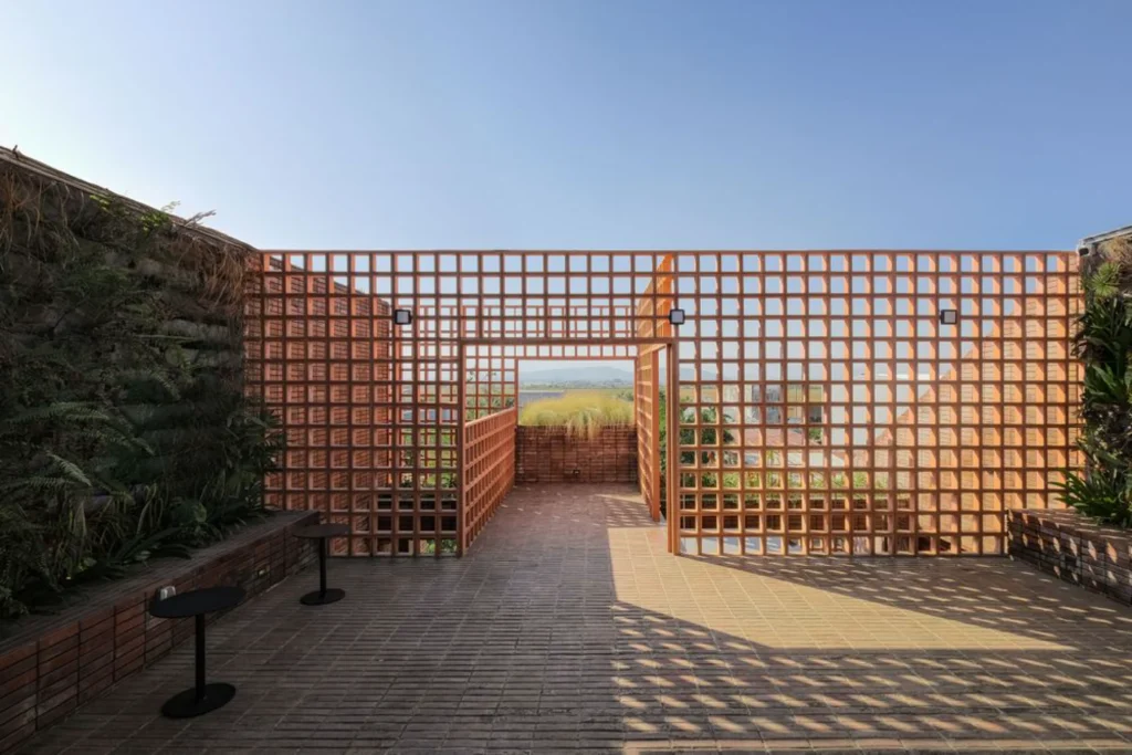 Outdoor terrace paved in terracotta brick and framed by a perforated screen wall