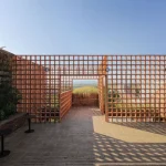 Outdoor terrace paved in terracotta brick and framed by a perforated screen wall