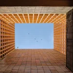Looking upward through the open terracotta screen grid toward the sky