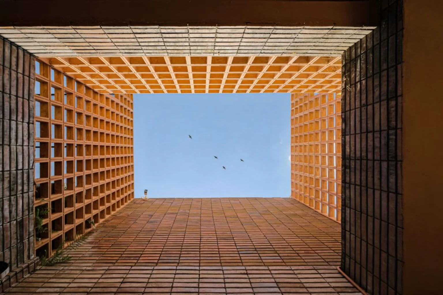 Looking upward through the open terracotta screen grid toward the sky