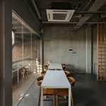 Interior working space with long table, brick screens and natural light