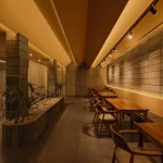 Ground-floor coffee bar and seating area with warm lighting and stone surfaces