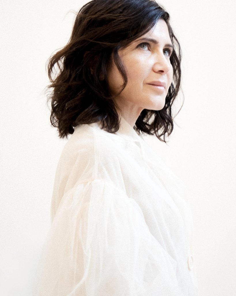 Portrait of Farshid Moussavi looking to the side, wearing a white blouse against a light background