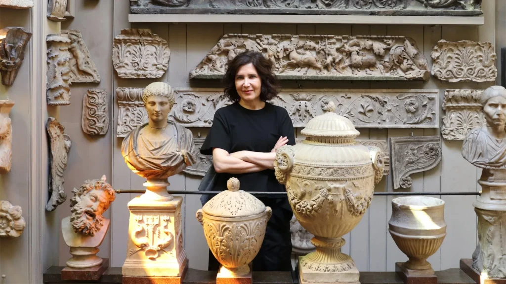 Farshid Moussavi standing with arms crossed among classical plaster casts and architectural fragments
