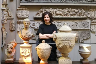 Farshid Moussavi standing with arms crossed among classical plaster casts and architectural fragments
