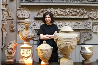 Farshid Moussavi standing with arms crossed among classical plaster casts and architectural fragments