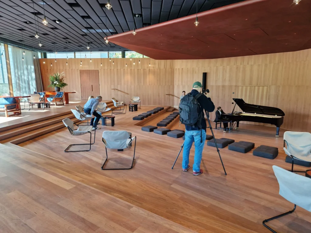 Open interior of the Ammann Pavilion with wooden floor, piano and people seated