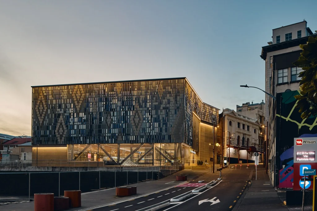 Street-level view of a station entrance with geometric façade patterning at dusk