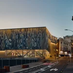 Street-level view of a station entrance with geometric façade patterning at dusk