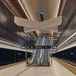 Underground platform level with clean lines, lighting and waiting passengers