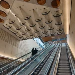 Escalators and perforated ceiling panels creating a rhythmic interior volume