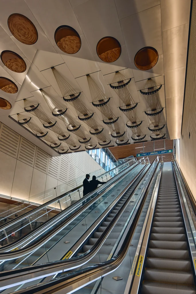 Escalators and perforated ceiling panels creating a rhythmic interior volume