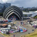 Ground-level view of the SEC Armadillo during an outdoor event with crowds and temporary structures