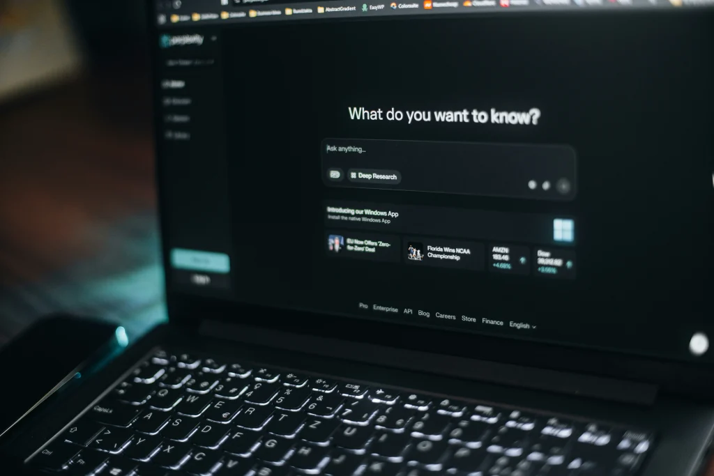 Laptop screen showing an AI research interface with the prompt “What do you want to know?”