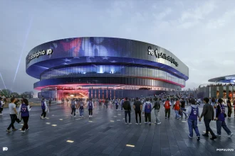 Night-time exterior rendering of the arena's stacked, ring-shaped bands lit in blue and red, with fans walking across the adjacent plaza toward the entrance.