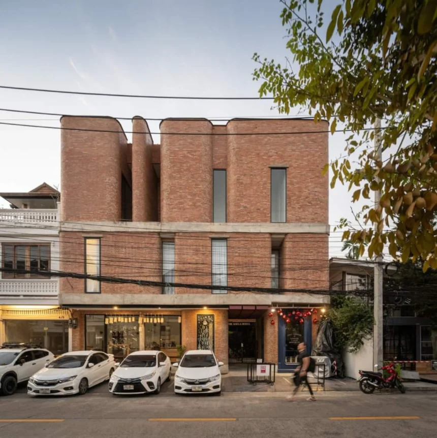 Street view of The Sayla Hotel showing the continuous red brick façade on a Chiang Mai soi