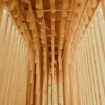 Looking upward through the dense grid of vertical timber pieces inside the pavilion