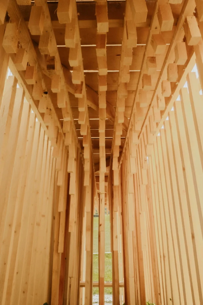 Looking upward through the dense grid of vertical timber pieces inside the pavilion
