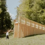Distant view of the timber pavilion on the hillside with a person standing nearby
