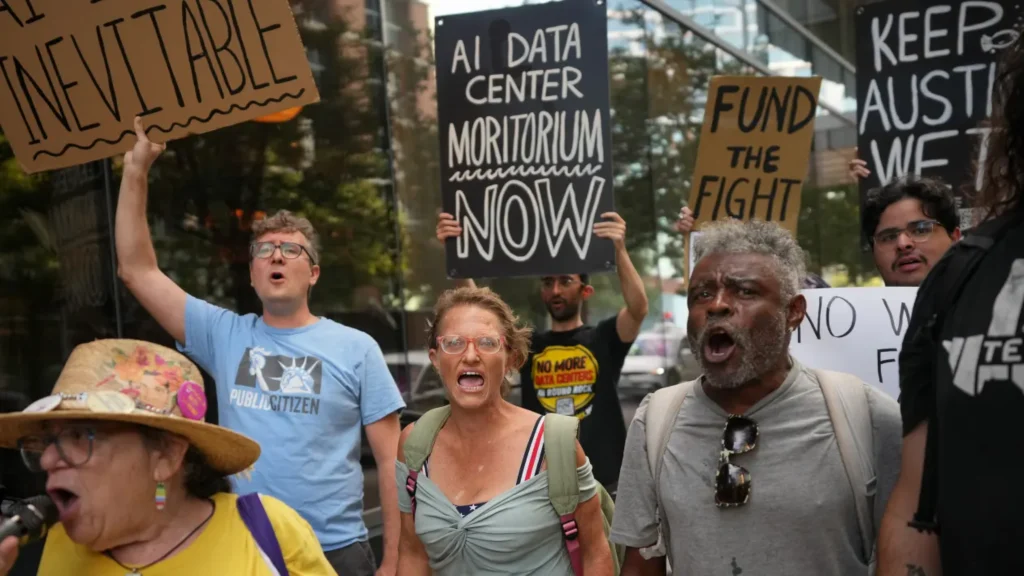 Group of people holding protest signs against data center development outside a downtown hotel