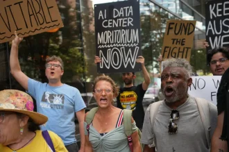 Group of people holding protest signs against data center development outside a downtown hotel