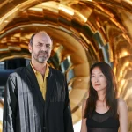 Artists Marco Canevacci and Yena Young standing inside the golden coils of auruBOROS