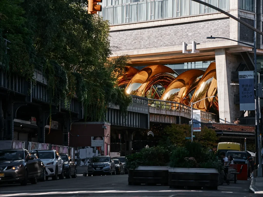 auruBOROS golden coils rising beside High Line walkers and city buildings