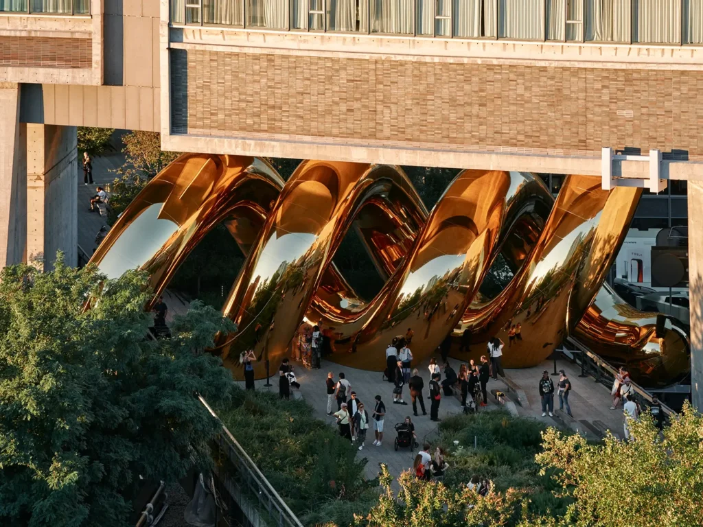 Side view of the interlocking golden volumes against brick buildings and trees