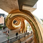 Close-up of the curved golden membrane reflecting trees and sky