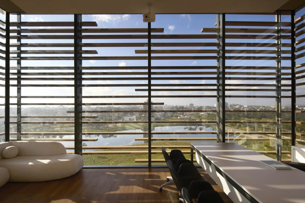 Interior view through the brise facade showing filtered natural light and outdoor landscape