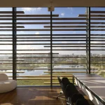 Interior view through the brise facade showing filtered natural light and outdoor landscape
