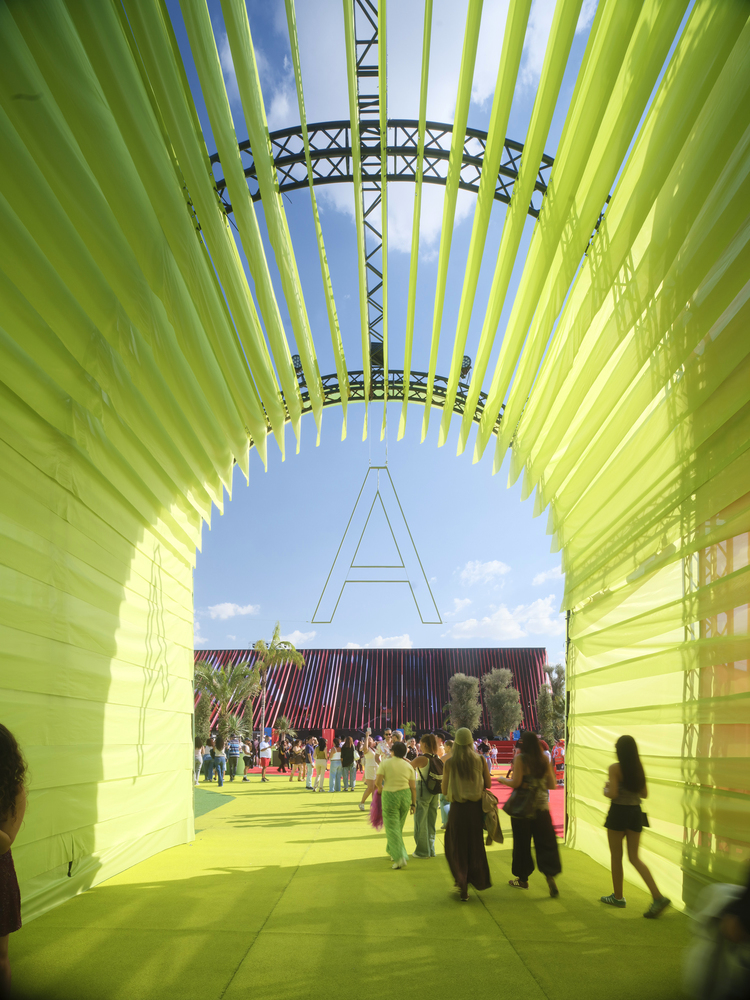 BIG Turns Madrid into Macondo Park for Shakira’s Residency_View through a bright yellow fabric tunnel framing the red stadium in the distance