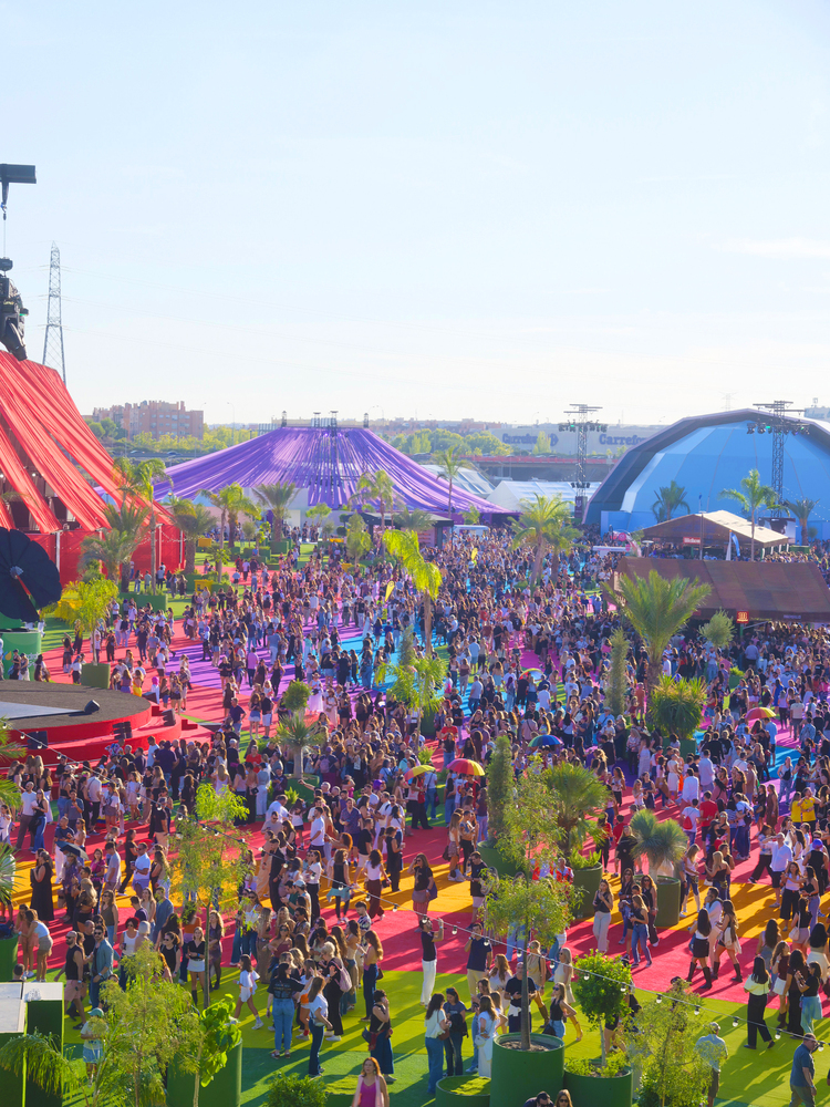 BIG Turns Madrid into Macondo Park for Shakira’s Residency_Wide aerial view of dense crowds on rainbow pathways with purple and blue fabric structures beyond