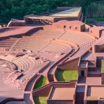 Aerial view of the reddish-brown amphitheater seating curving into the green hillside