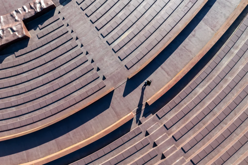 Earth Valley Theater: Overhead view of curved concrete seating tiers with a single person walking along a ramp