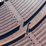 Overhead view of curved concrete seating tiers with a single person walking along a ramp