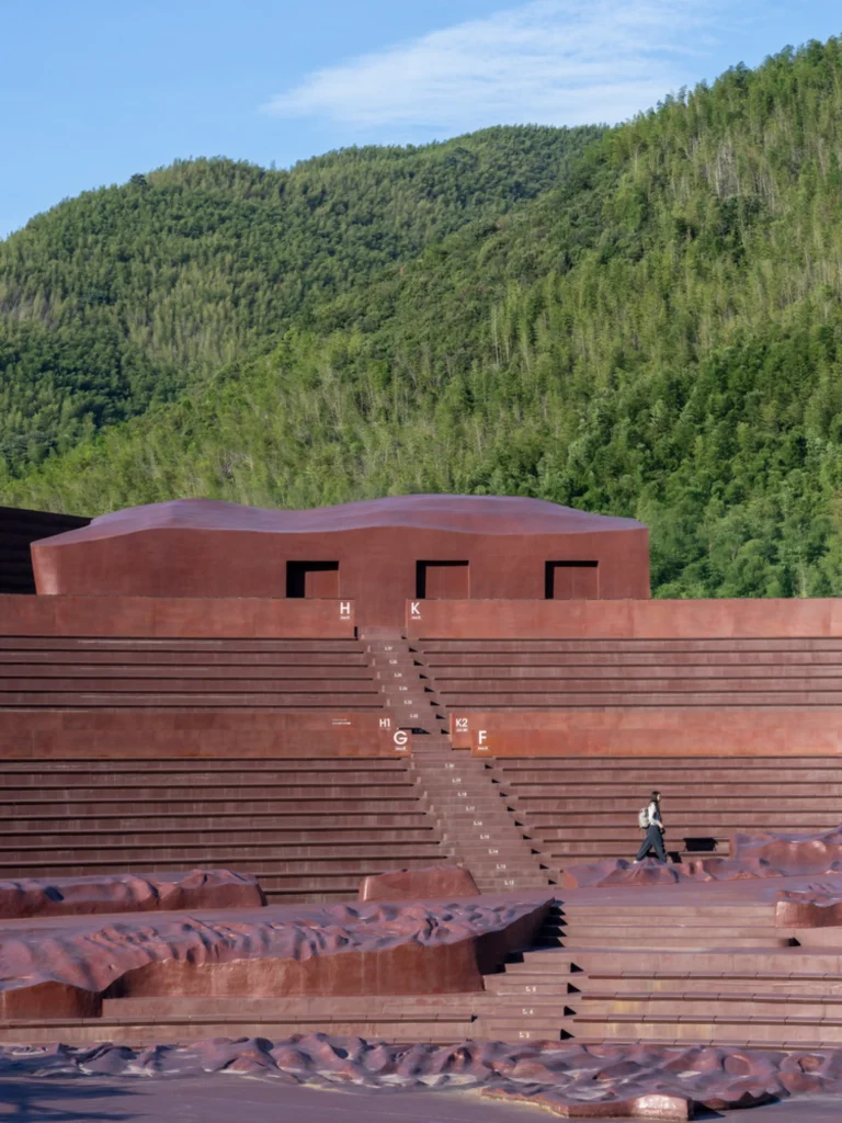 Earth Valley Theater: Stepped seating and undulating landforms leading up to a building volume against green hills