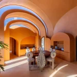Warm-toned vaulted interior with arched doorways and dining area at Gelareh House