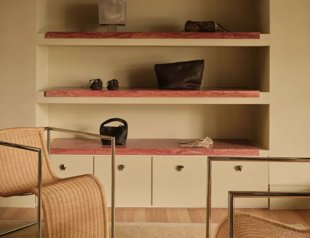Custom cabinet handles and built-in shelving with pink stone surfaces, woven furniture, and minimalist storage details in a contemporary interior