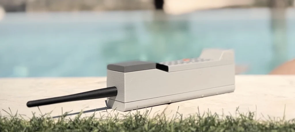 ADHD ONE handset resting on a stone surface beside a swimming pool with its long black antenna extended