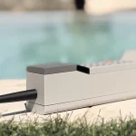 ADHD ONE handset resting on a stone surface beside a swimming pool with its long black antenna extended