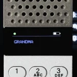 Close-up of the OLED display showing an incoming call from “GRANDMA” with battery and signal indicators